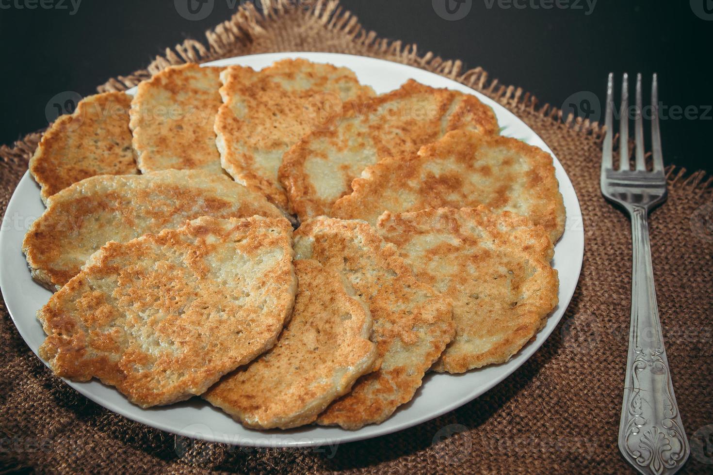 frittelle di patate su un piatto e forchetta su sfondo di lino foto