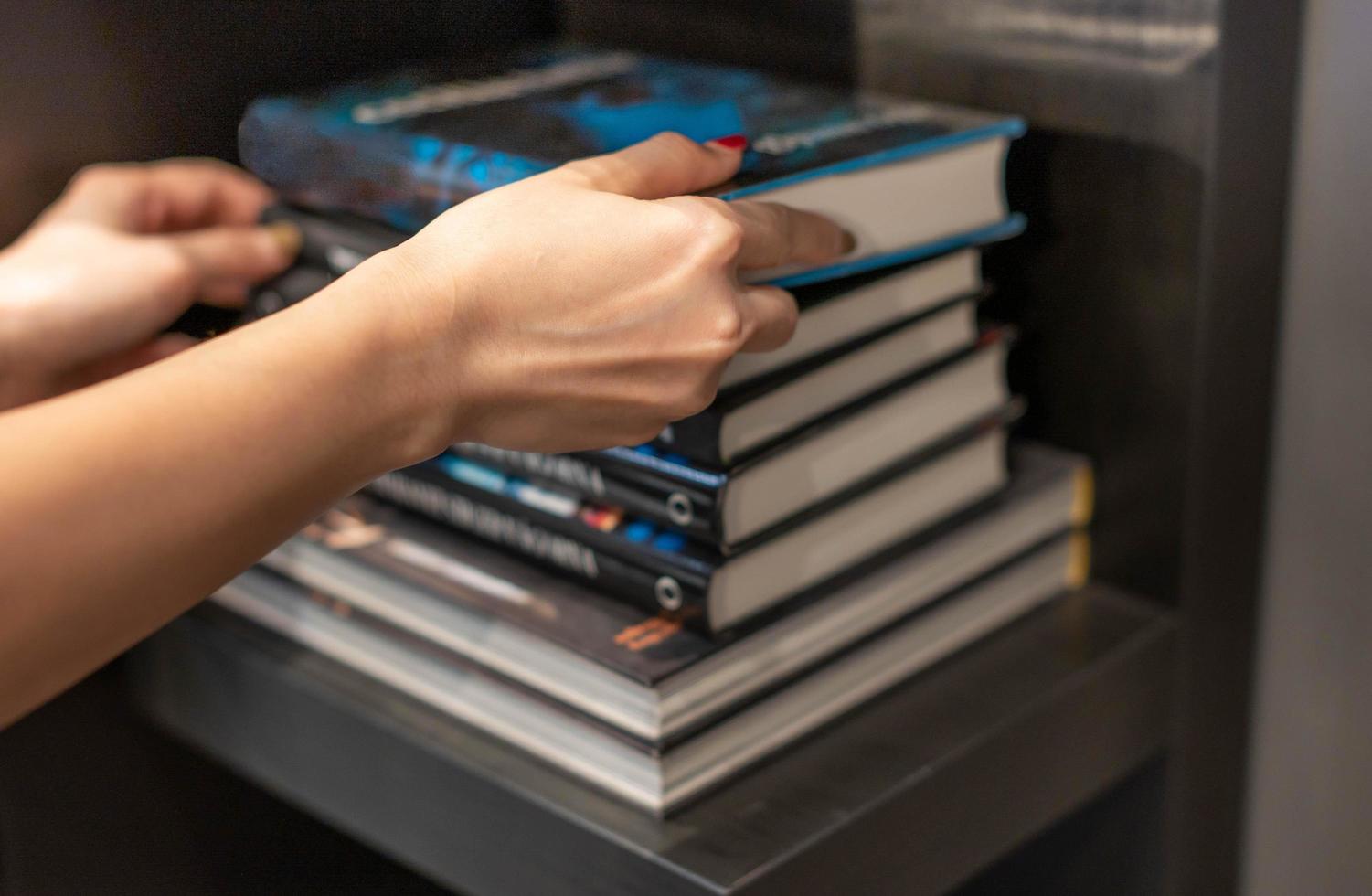 femmina mano raccolta nuovo libro su mensola nel libreria negozio. personale informazione libro o rivista per attività commerciale o formazione scolastica ricerca. acquisto ufficio forniture concetto foto