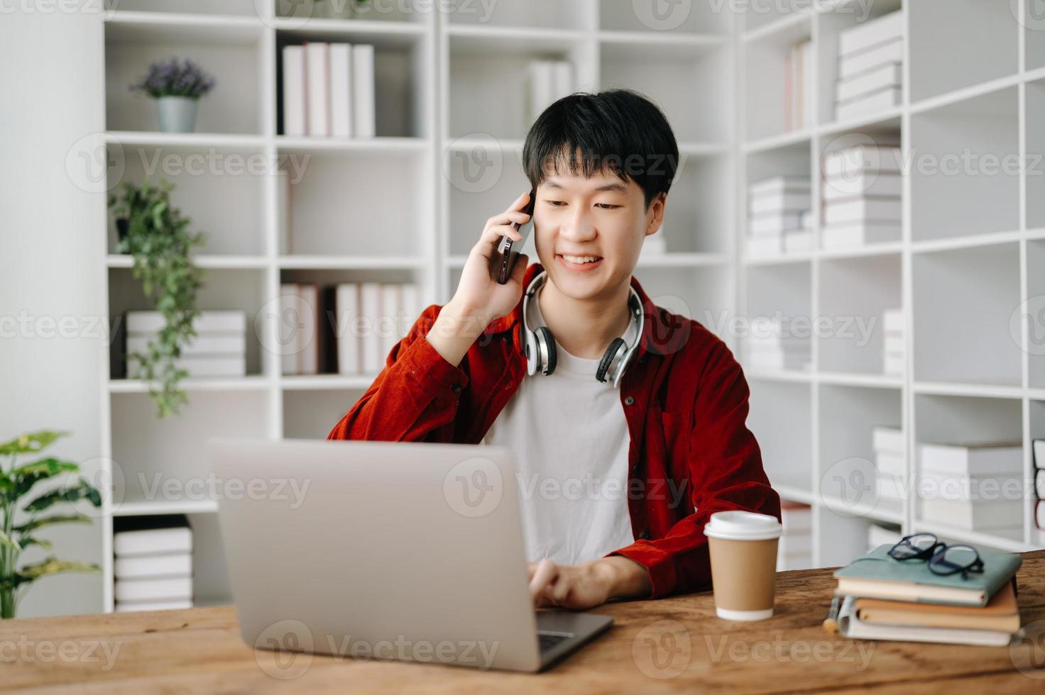 giovane attraente asiatico uomo sorridente pensiero pianificazione scrittura nel taccuino, tavoletta e il computer portatile Lavorando a partire dal casa a casa ufficio foto