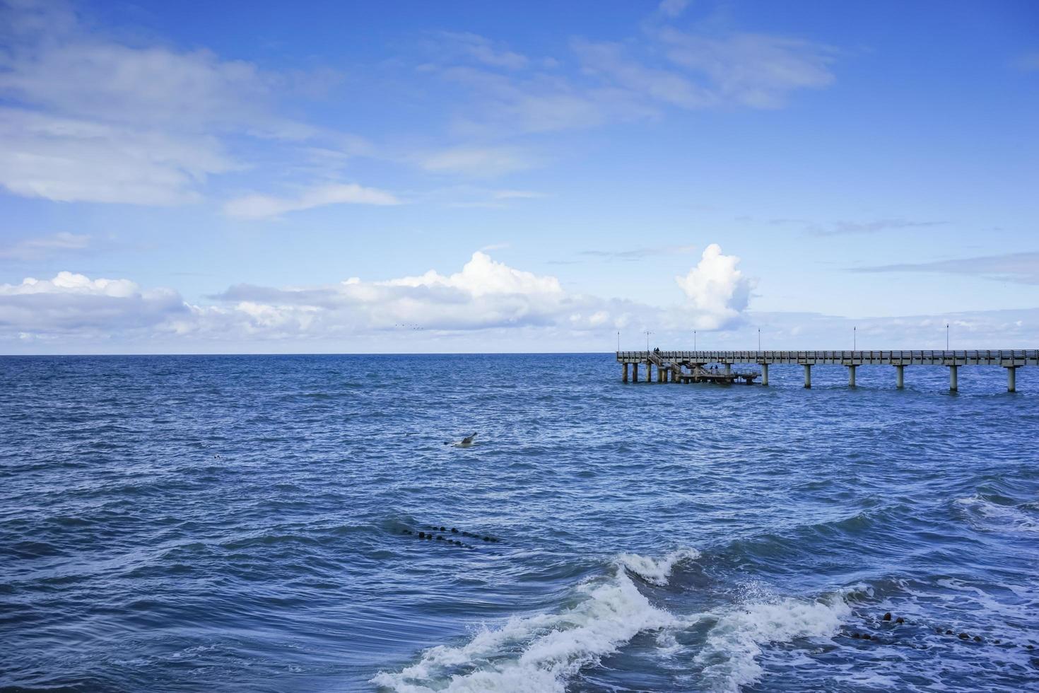 paesaggio marino che si affaccia sul lungo molo della località turistica con persone che camminano. foto