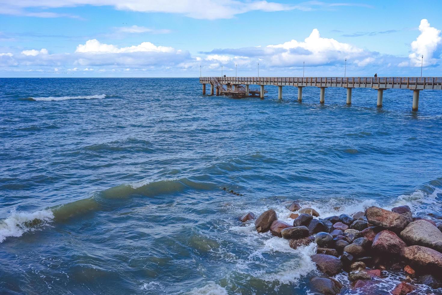 paesaggio marino che si affaccia sul lungo molo della località turistica con persone che camminano. foto