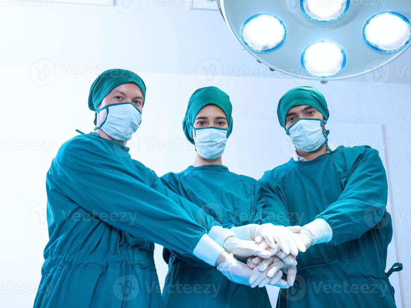 ospedale clinica emergenza operazione leggero camera interno medico infermiera personale assistenza femmina maschio persona donna uomo persone toccare mano lavoro di squadra gruppo Guarda a telecamera indossare uniforme maschera verde colore supporto foto