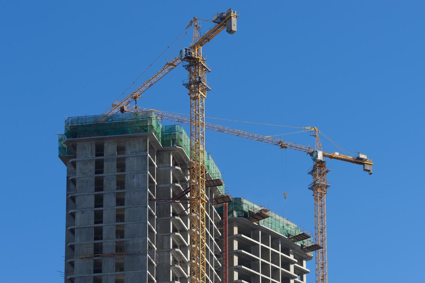 casa in costruzione e gru contro il cielo blu. foto