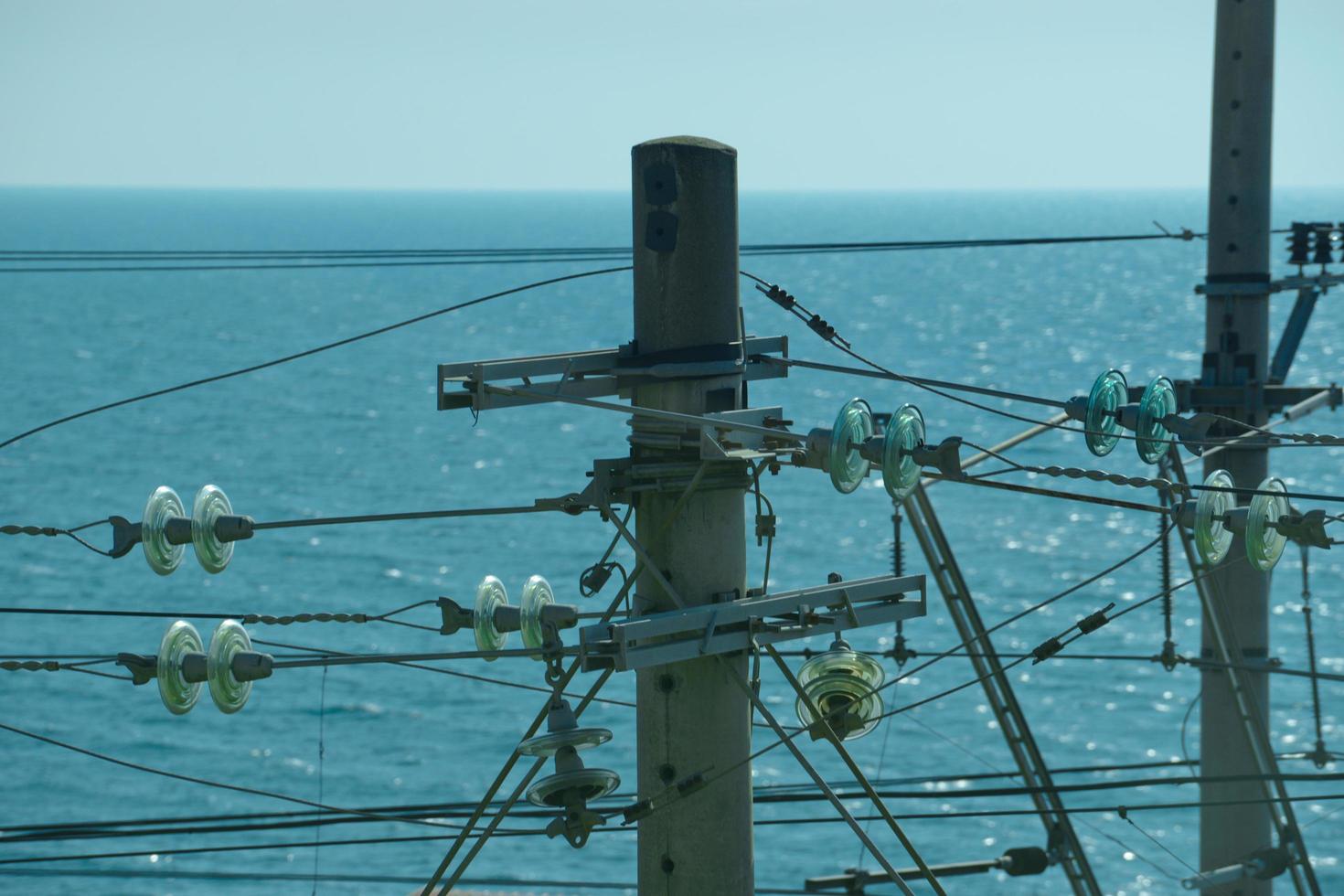 linea elettrica ad alta tensione contro il mare blu e il cielo limpido foto