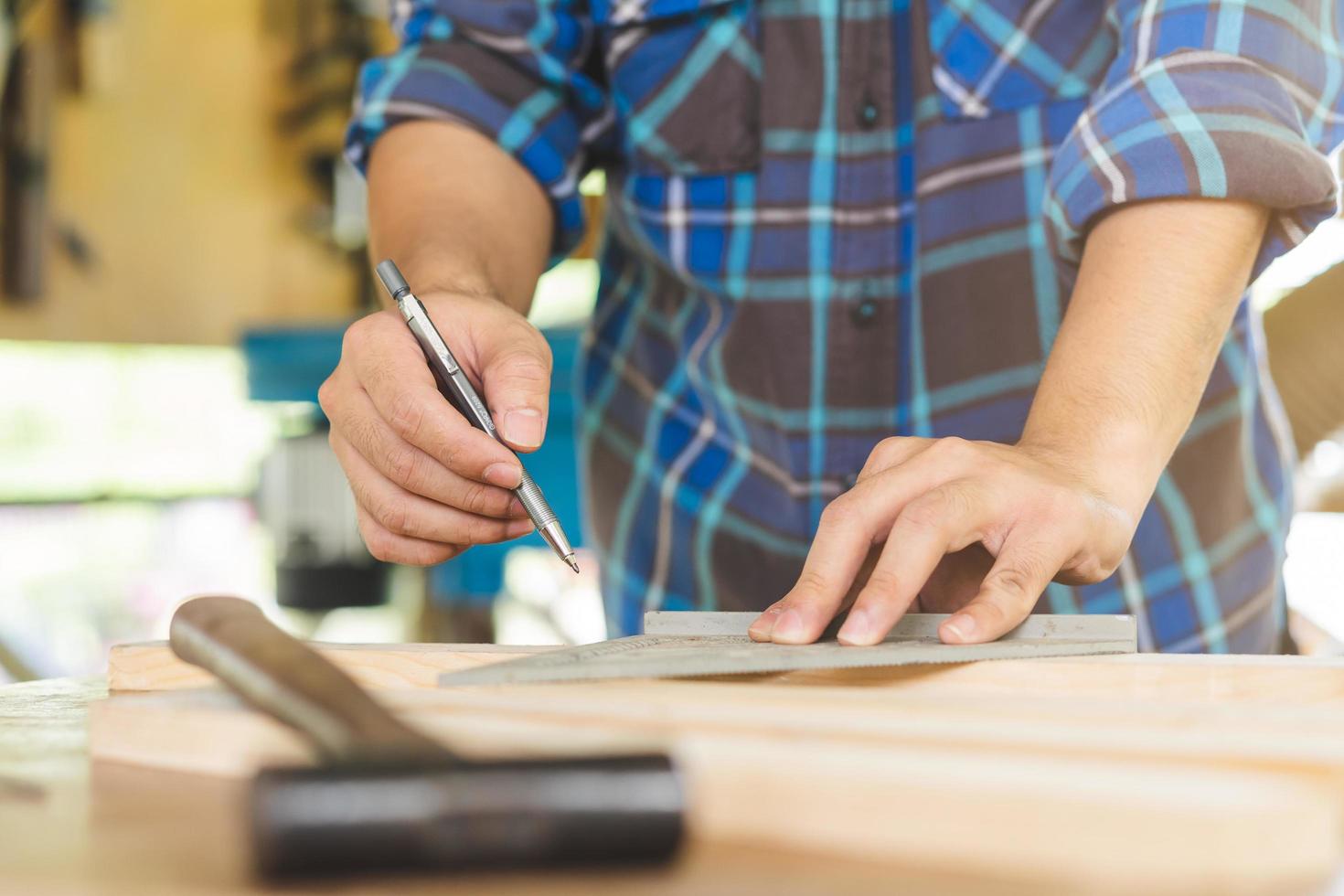 carpenteria professionale, mano di asiatico giovane uomo, maschio falegname uso righello misurare, attrezzo su tavola legna nel piccolo negozio. lavorazione del legno, mobilia fabbricazione, costruzione industria. proprietario piccolo attività commerciale le persone. foto