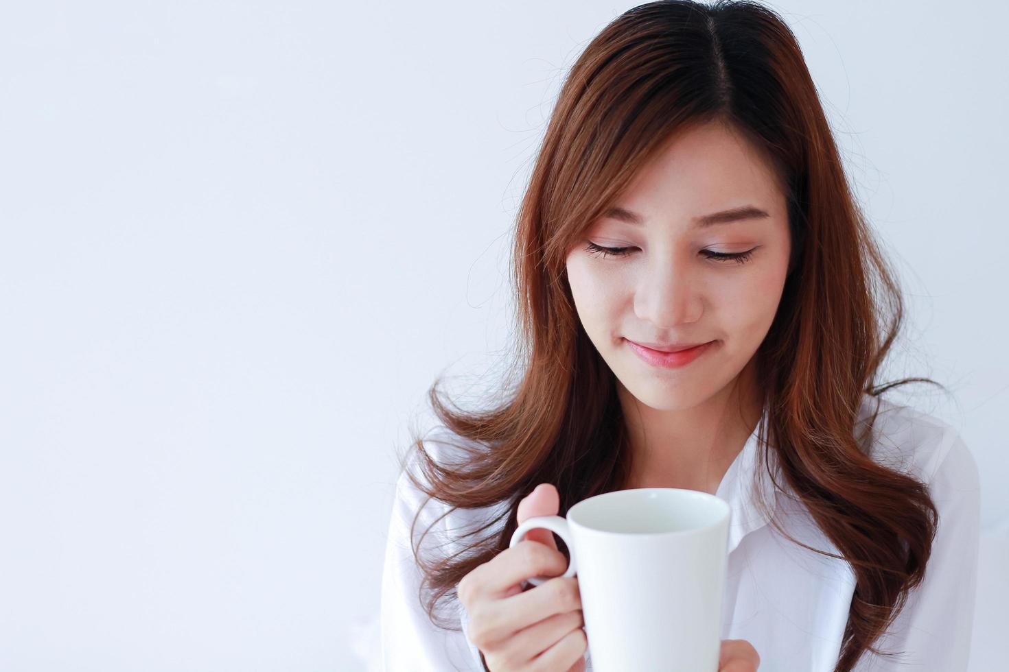 Ritratto di giovane donna asiatica in possesso di una tazza di caffè su uno sfondo bianco. foto