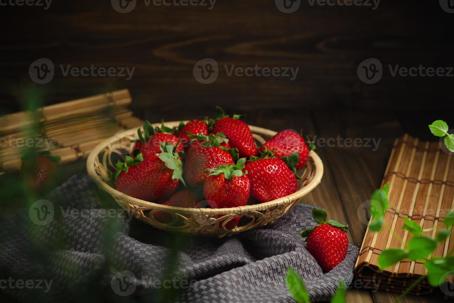 di vimini cestino con dolce rosso fragole su un' buio di legno tavolo. foto