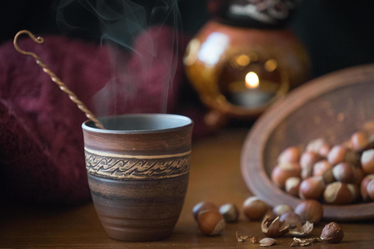 tazza e le nocciole noci sparse su una superficie di legno. foto