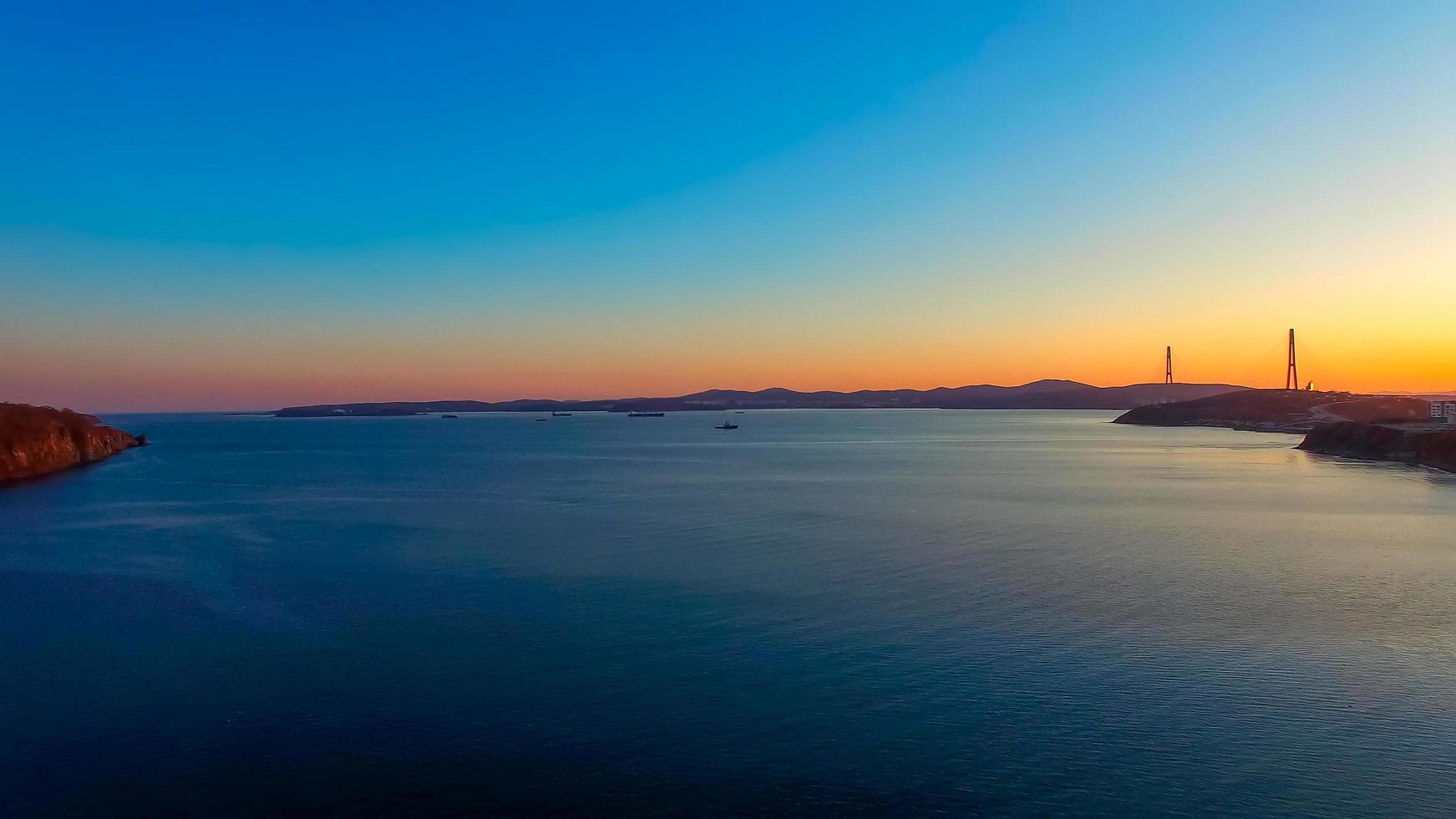 vista sul mare con vista tramonto e ponte russo all'orizzonte. foto