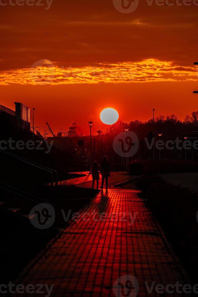 rosso tramonto nel il città con un' strada e a piedi coppia di persone nel amore foto