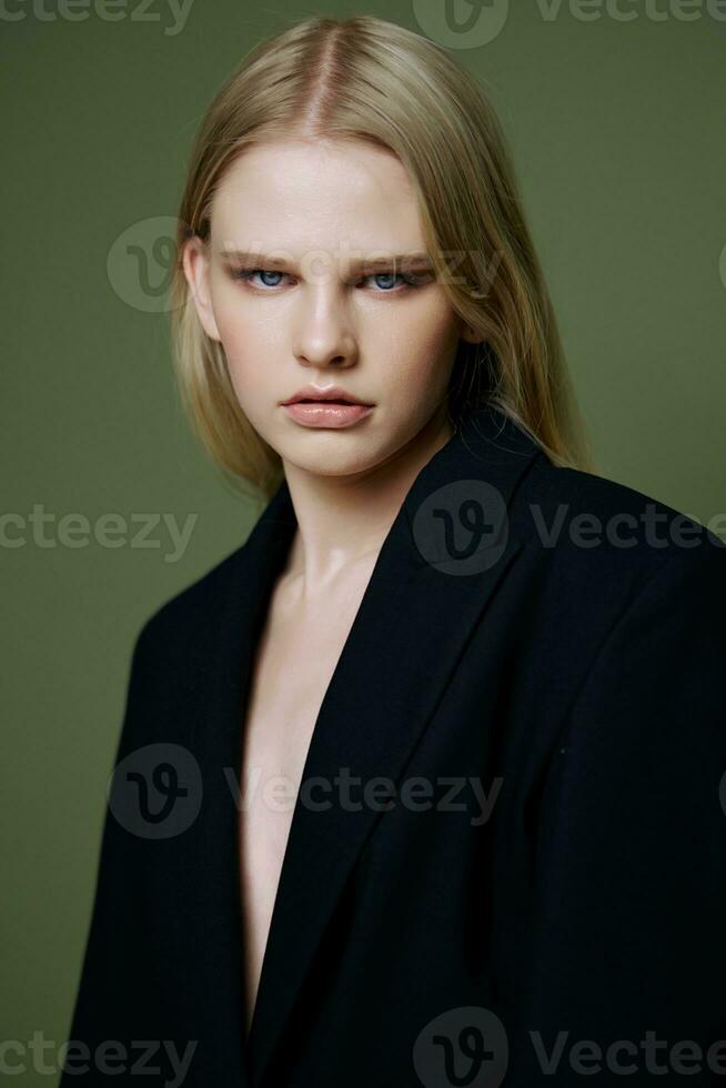 ritratto di un' ragazza nel un' nero giacca in posa su un' verde sfondo nel il studio. un' concetto per mercatini e capi di abbigliamento Marche. foto