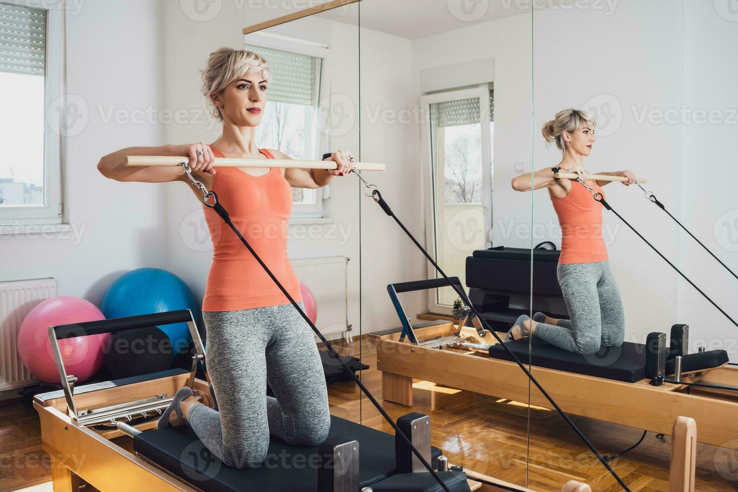 bionda donna è esercizio su pilates riformatore letto nel sua casa. foto