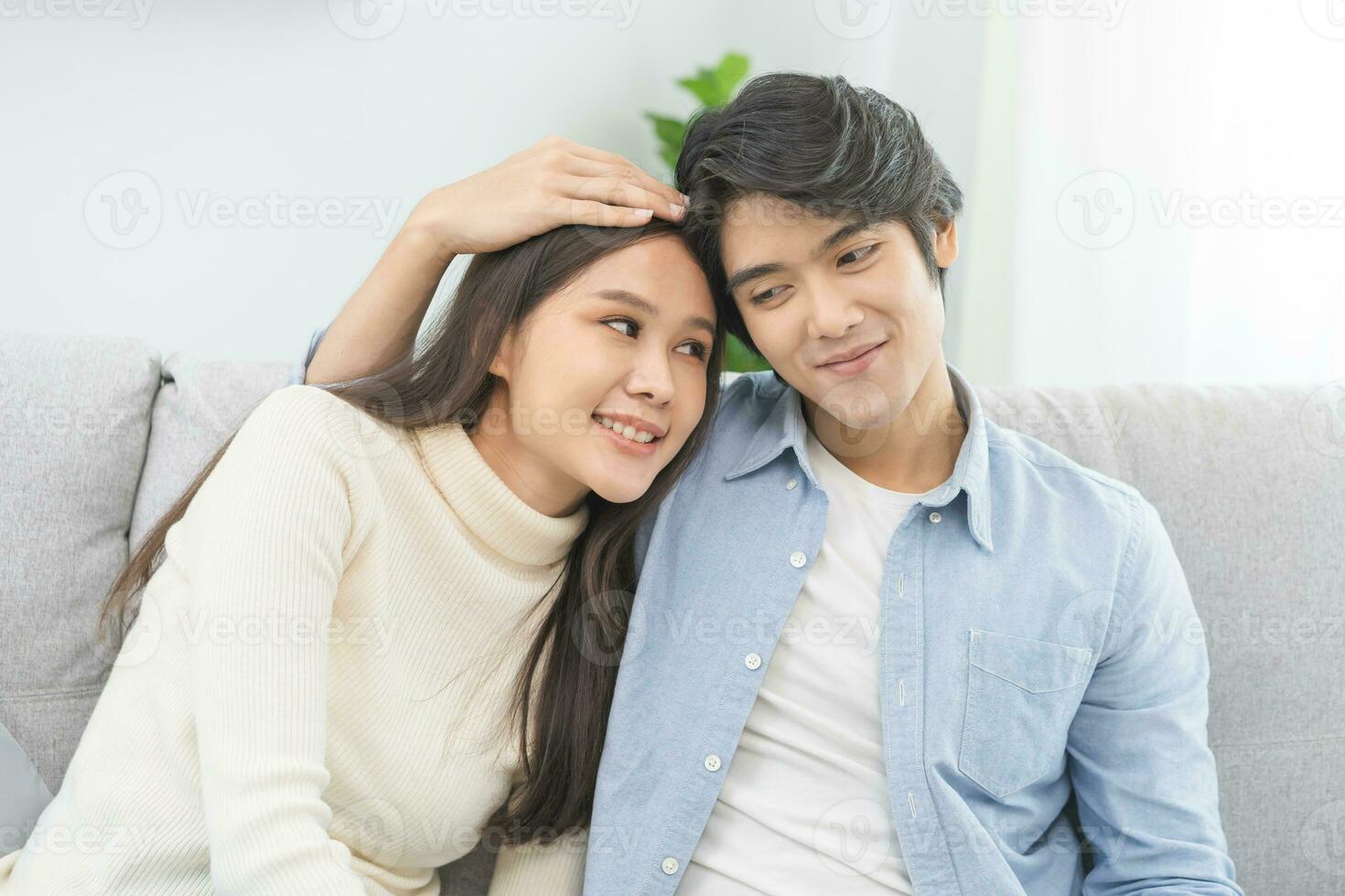 felice, asiatico giovane coppia amore abbraccio, la spesa gratuito tempo insieme, bonding per ogni altro e sorridente romantico seduta su divano nel vivente camera a casa. fine settimana tempo libero attività di famiglia stile di vita. foto