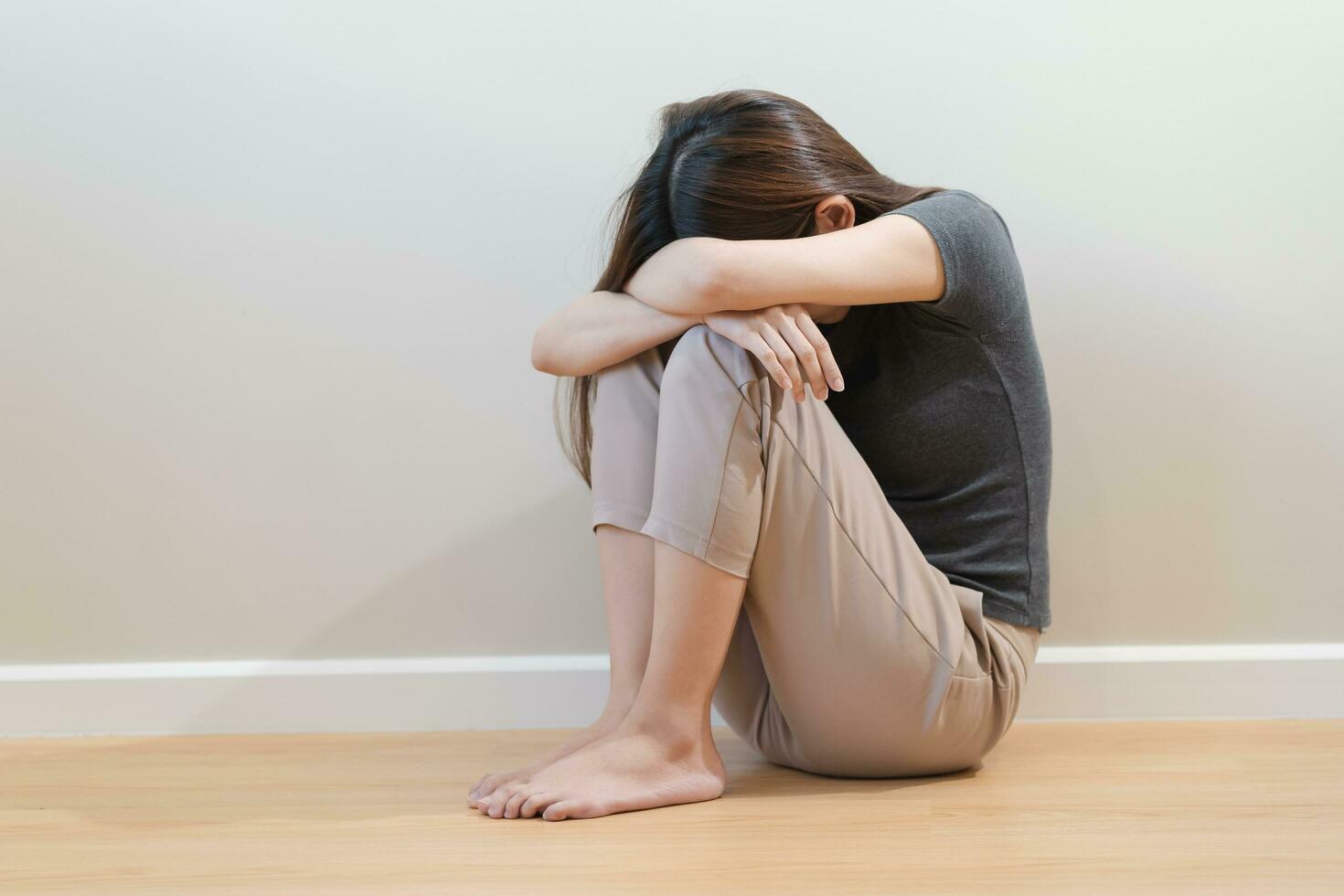 psicologico mentale Salute, depresso asiatico giovane donna, ragazza nascondiglio sua viso sensazione solitario, pensiero di problema, preoccupato sofferenza depressione, seduta solo su pavimento a casa, depressione le persone. foto