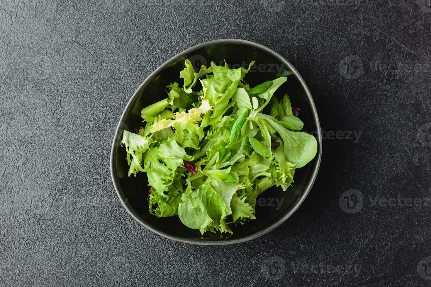 verde insalata le foglie nel ciotola su nero tavolo. foto