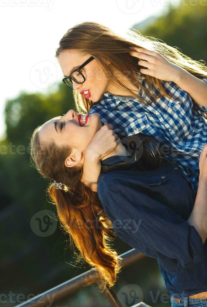 Due giocoso ragazze avendo divertimento all'aperto a tramonto leggero foto