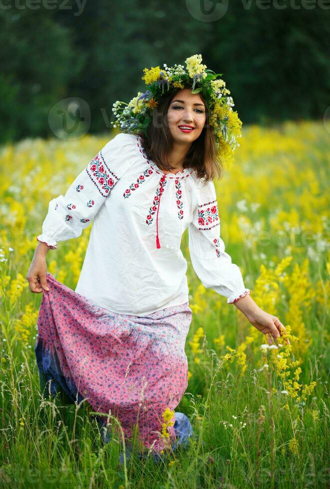 giovane sorridente ragazza nel ucraino costume con un' ghirlanda su il suo testa nel un' prato foto