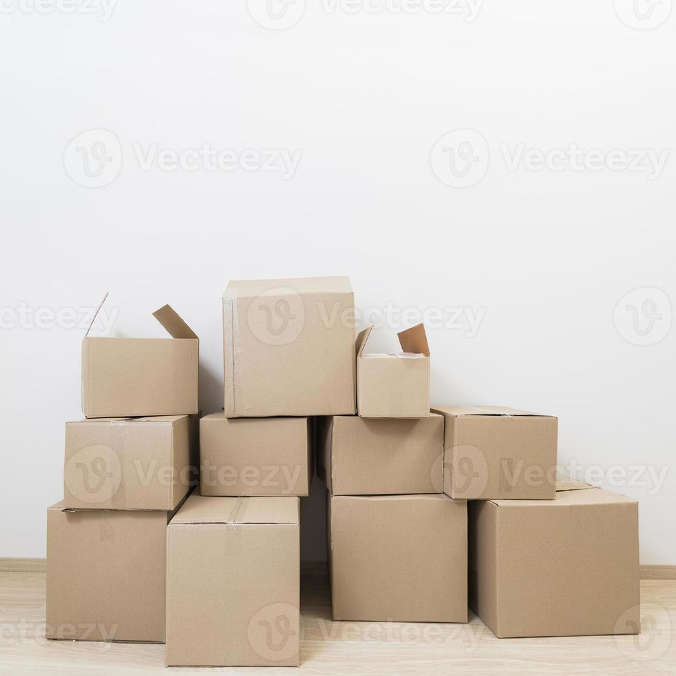 scatole di cartone in movimento impilate contro il muro bianco foto