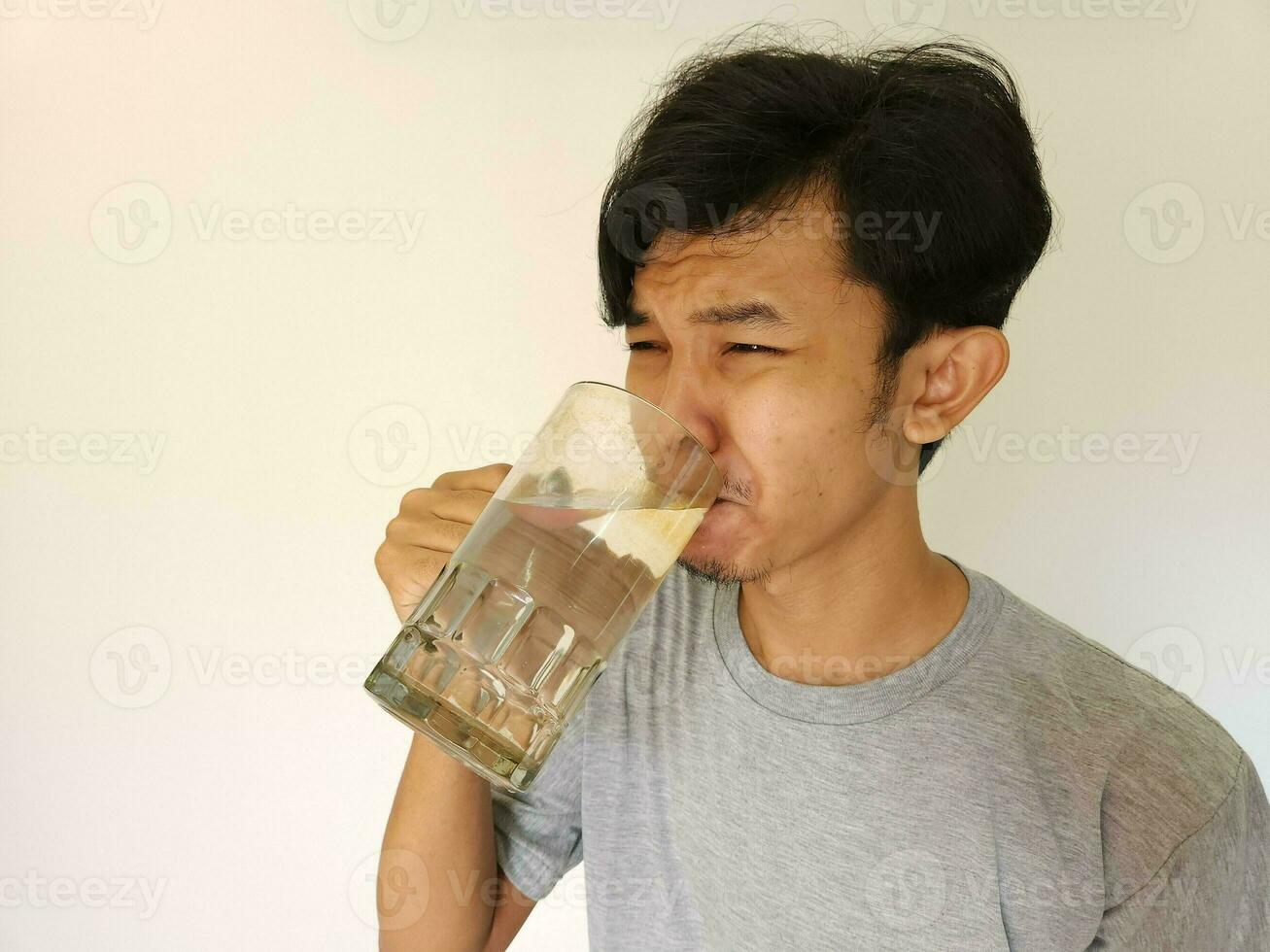 asiatico uomo potabile un' bicchiere di acqua foto