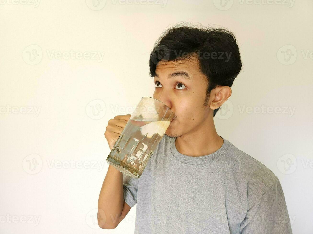 asiatico uomo potabile un' bicchiere di acqua foto