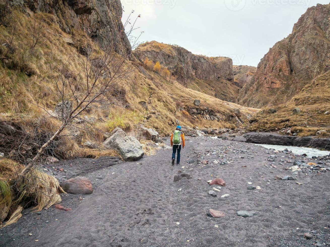 assolo il trekking lungo il asciutto letto di un' montagna fiume. autunno il trekking su sentiero solo Caucaso rocce. viaggio fotografo stile di vita, escursioni a piedi difficile traccia, avventura concetto nel autunno vacanza. foto