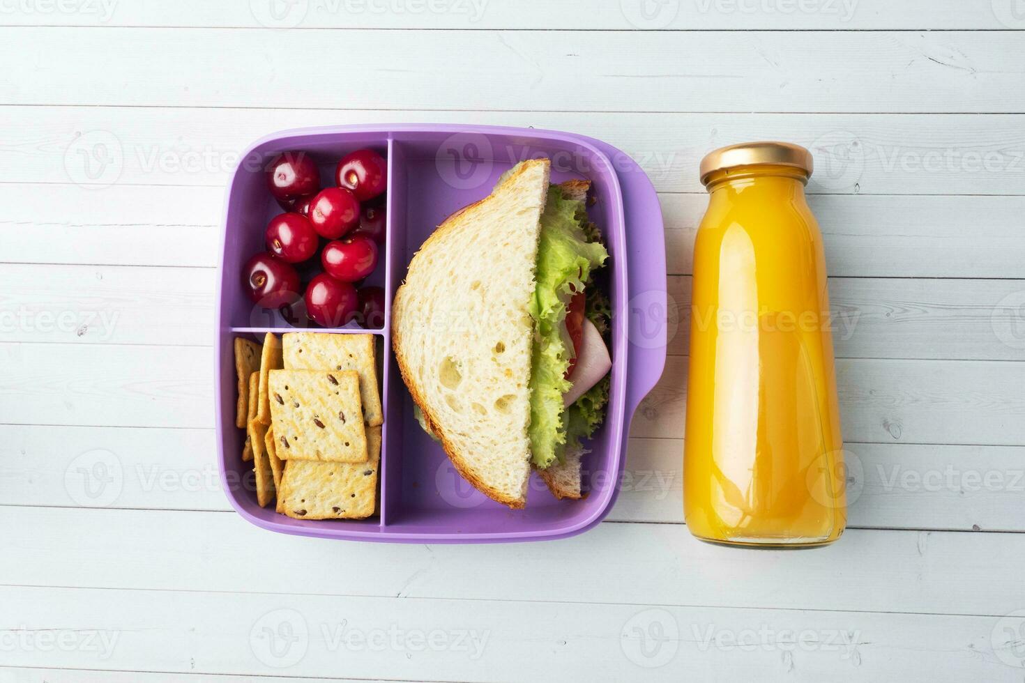 delizioso salutare Sandwich nel un' pranzo scatola, biscotti e ciliegie. prendere pranzo con voi per scuola o il ufficio. succo nel un' bottiglia e un Mela. foto