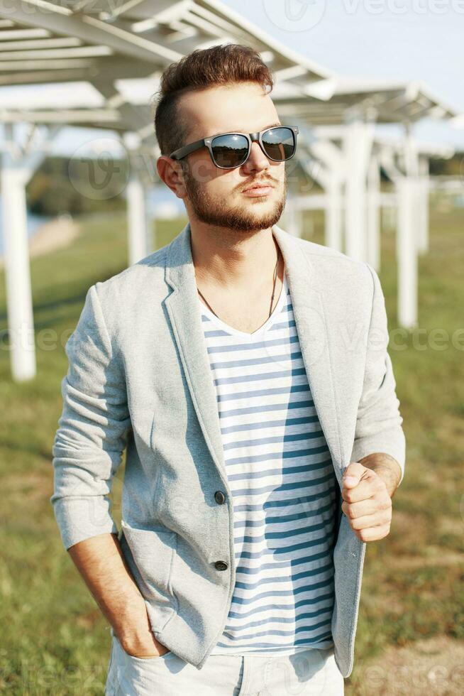 bello fricchettone tipo nel di moda giacca in posa su il spiaggia. foto