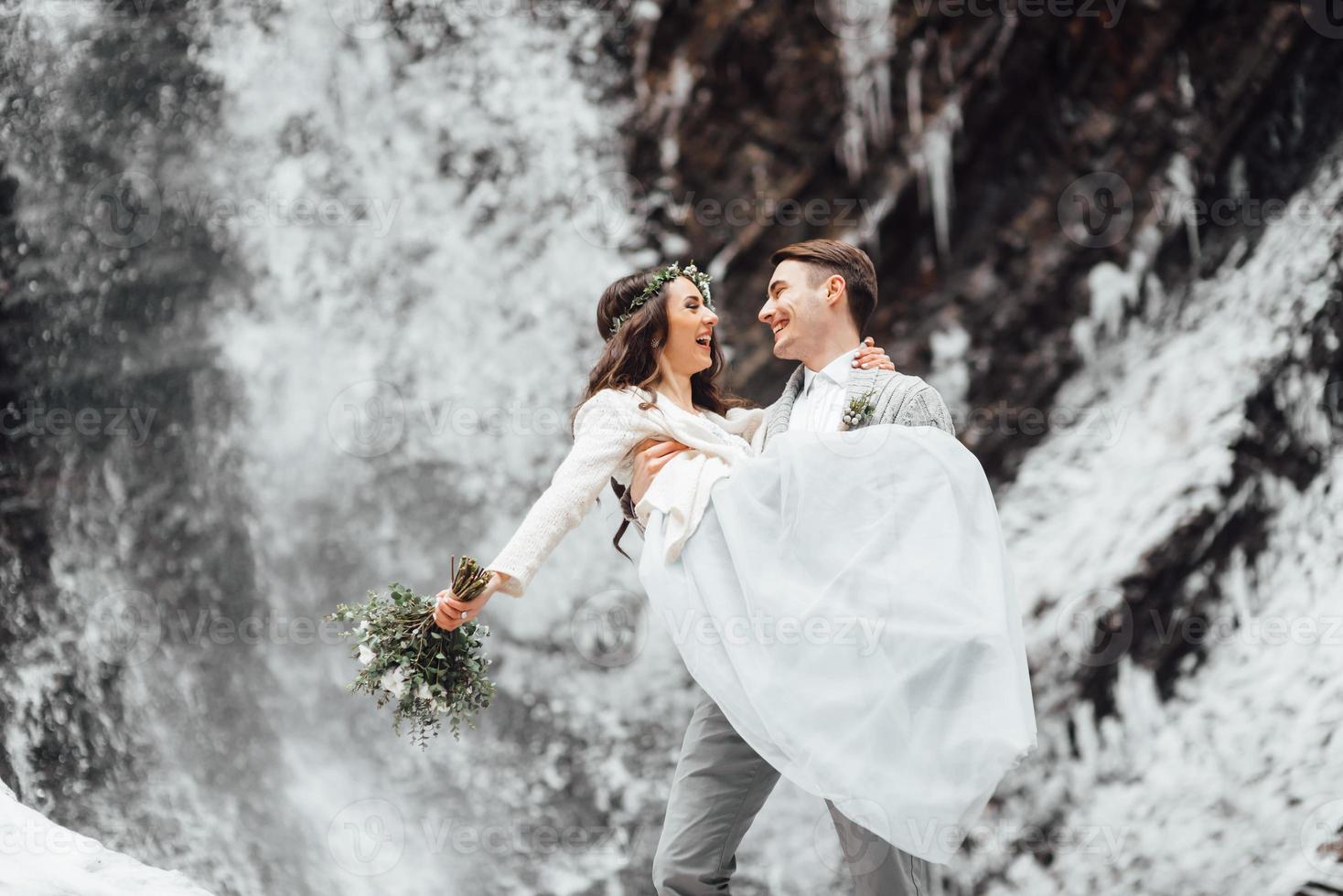 sposa e sposo sulla cascata di montagna foto