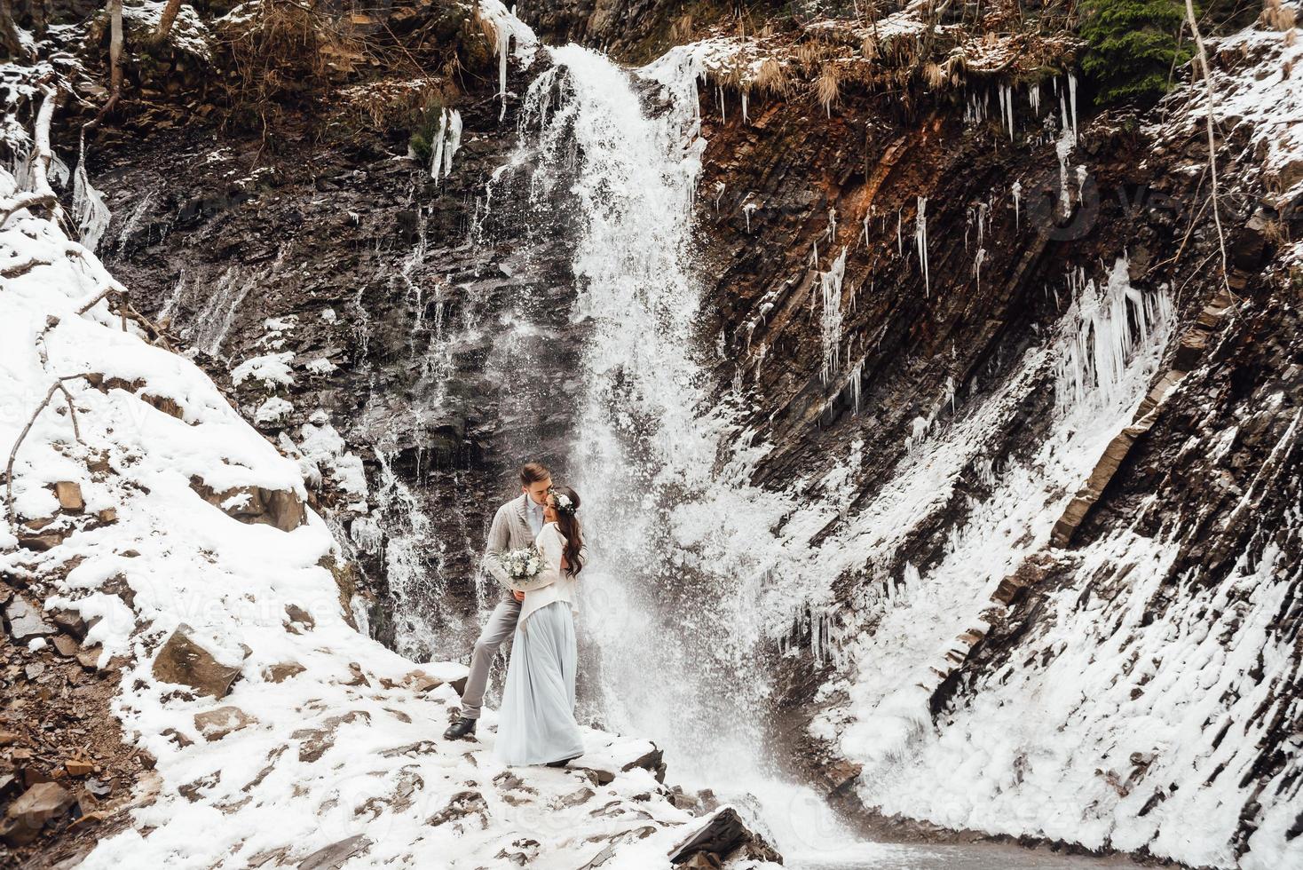 sposa e sposo sulla cascata di montagna foto