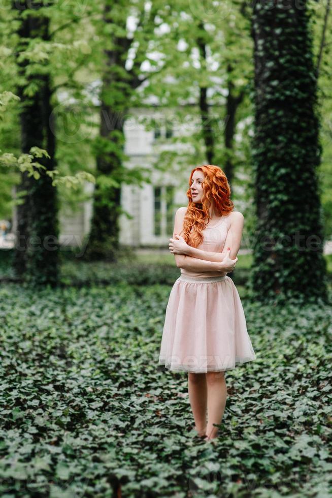 giovane ragazza dai capelli rossi che cammina in un parco tra gli alberi foto