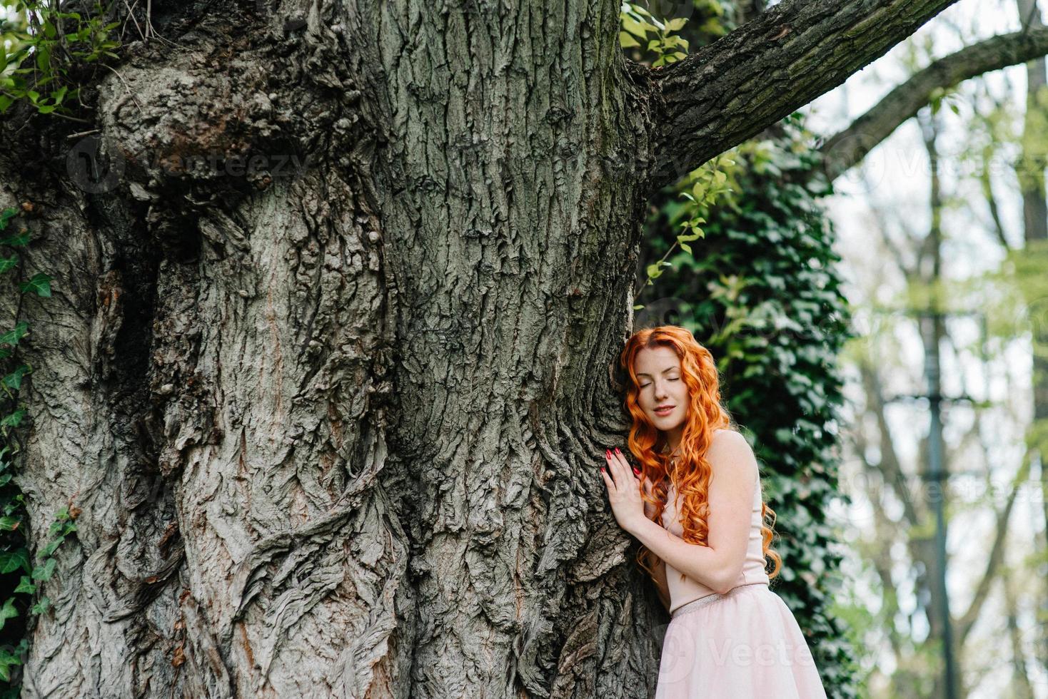 giovane ragazza dai capelli rossi che cammina in un parco tra gli alberi foto