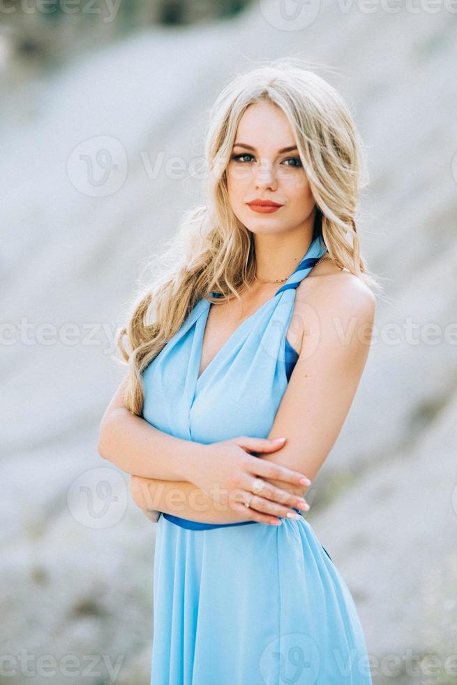 ragazza bionda in un abito azzurro in una cava di granito foto