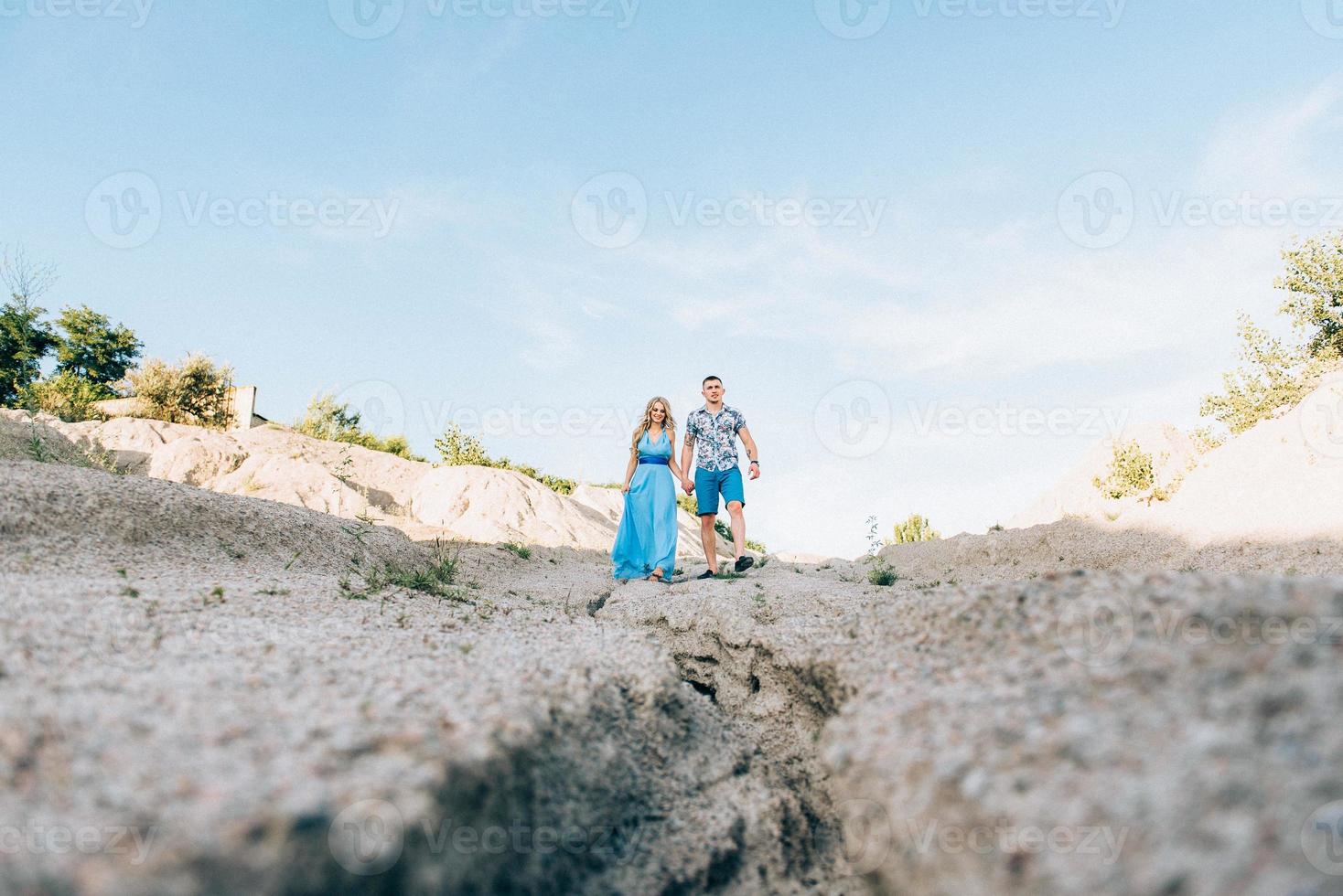 ragazza bionda in un vestito azzurro e un ragazzo con una camicia leggera in una cava di granito foto