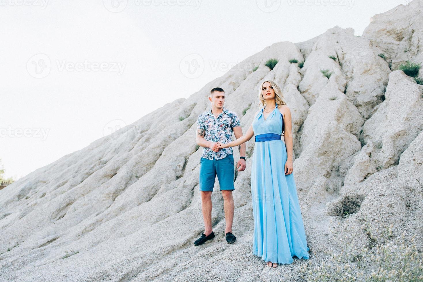 ragazza bionda in un vestito azzurro e un ragazzo con una camicia leggera in una cava di granito foto