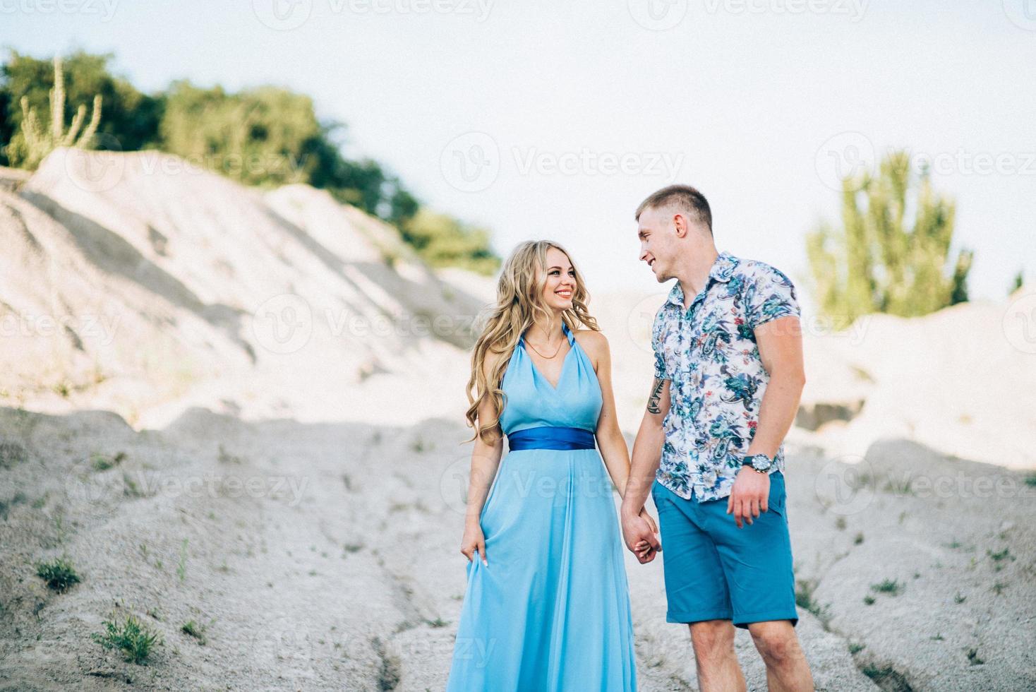 ragazza bionda in un vestito azzurro e un ragazzo con una camicia leggera in una cava di granito foto