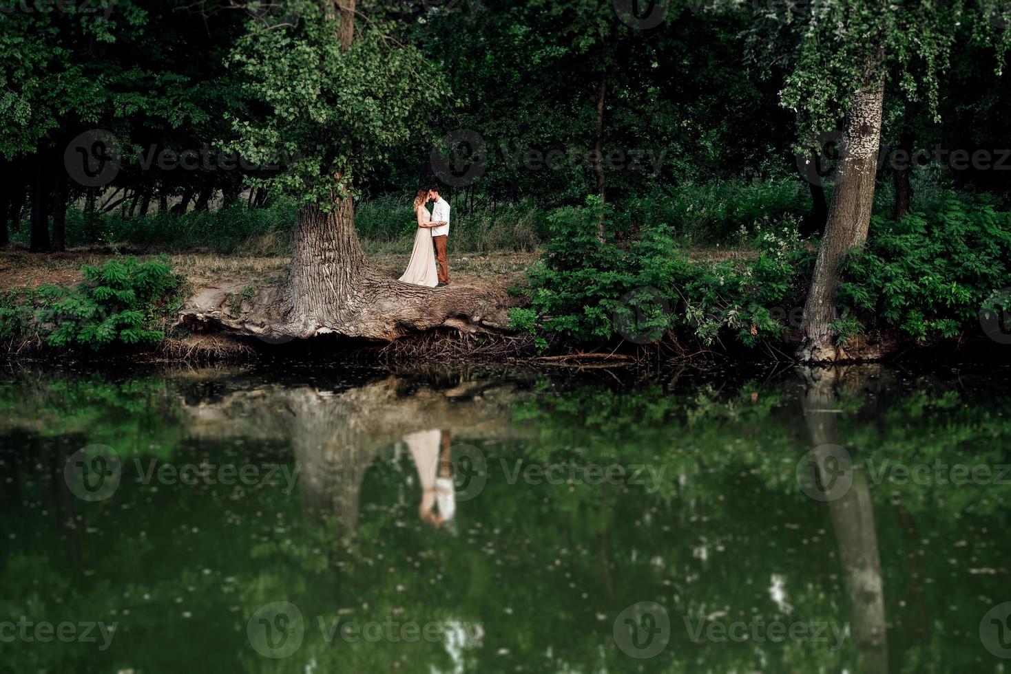 un ragazzo e una ragazza stanno camminando lungo le rive di un fiume selvaggio ricoperto di vegetazione foto