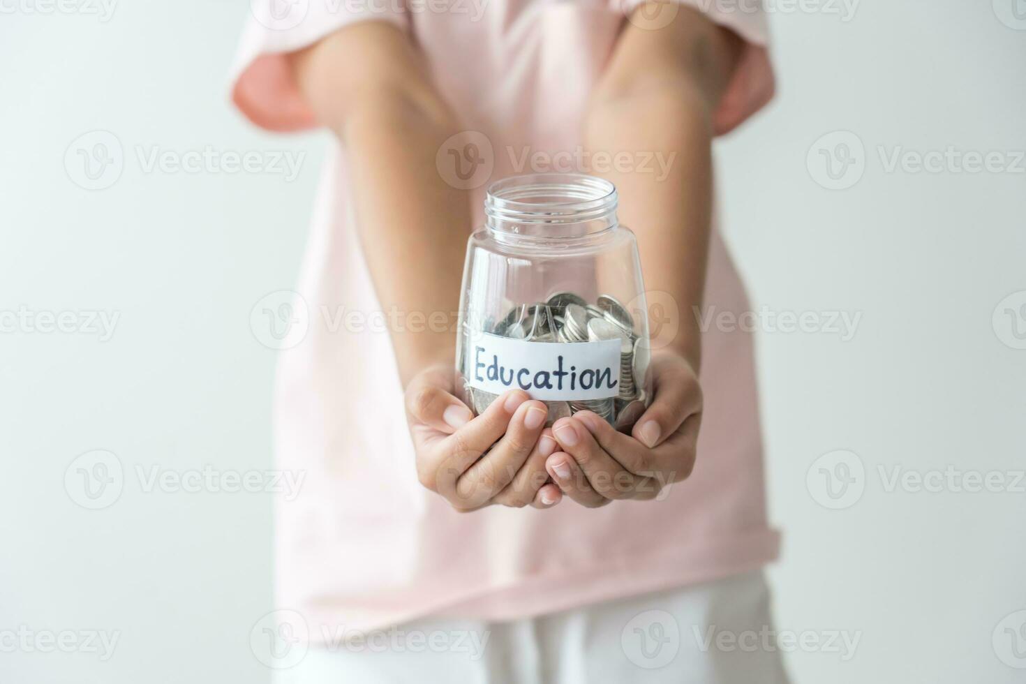 ragazzo Tenere sua Salvataggio monete vaso concetto di risparmi i soldi per futuro formazione scolastica scuola ammissione tassa. poco figlia imparare per Salva i soldi. foto