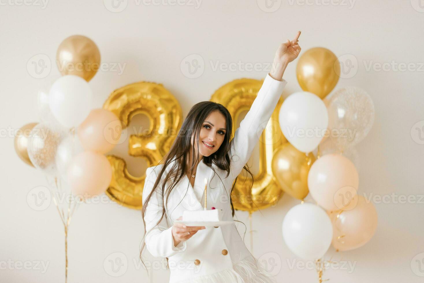 giovane caucasico donna Tenere un' torta con un' candela nel onore di il trentesimo compleanno nel un' elegante bianca vestito con piume foto