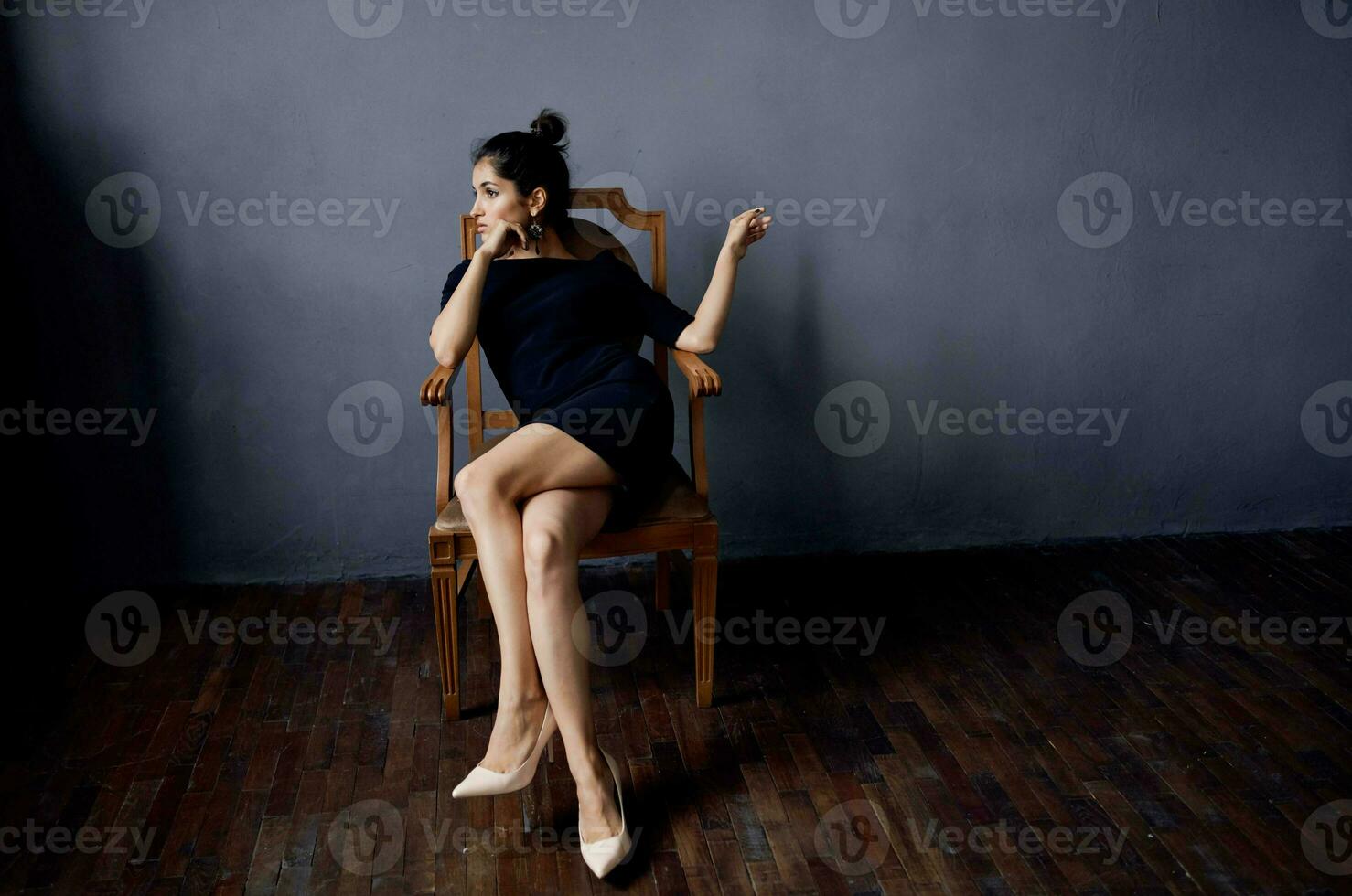 brunetta nel un' nero vestito vicino il sedia lusso moda stile di vita studio foto