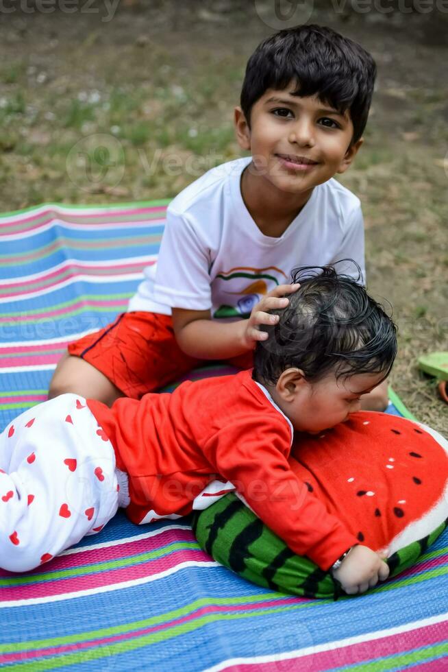 Due contento ragazzi nel società parco, contento asiatico fratelli chi siamo sorridente felicemente insieme. fratelli giocare all'aperto nel estate, migliore gli amici. bambino piccolo bambino ragazzo giocando con il suo contento fratello nel il giardino foto