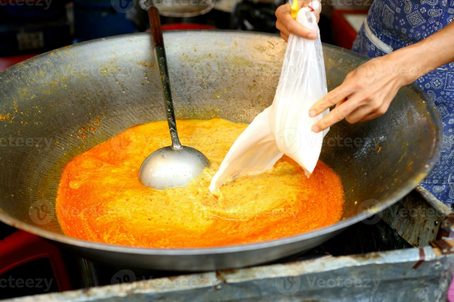 cucinando cibo versare il Noce di cocco latte in il d'oro arancia curry nel il padella . foto