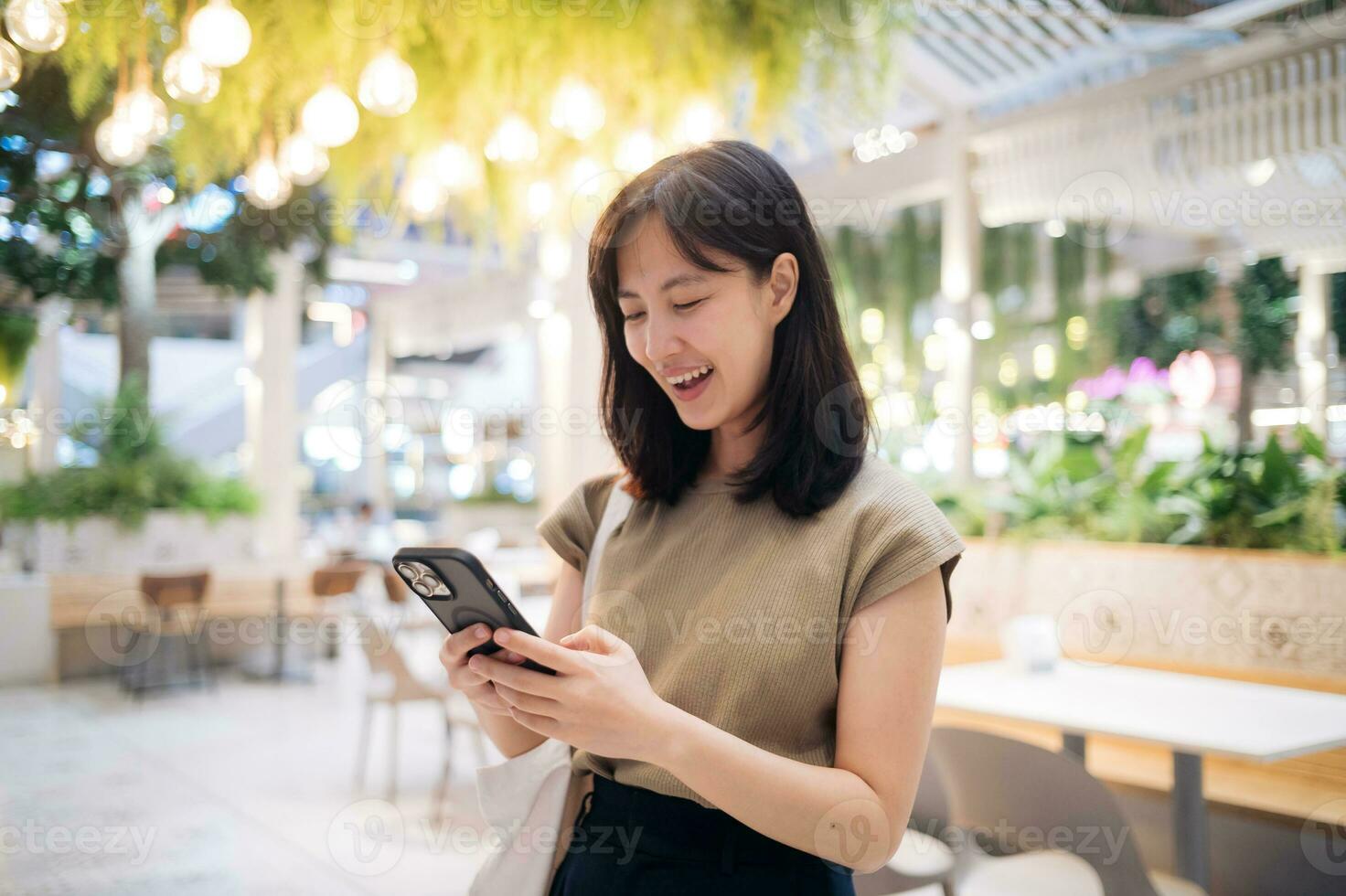 ritratto bellissimo giovane asiatico donna con inteligente mobile Telefono nel caffetteria a shopping centro commerciale. foto