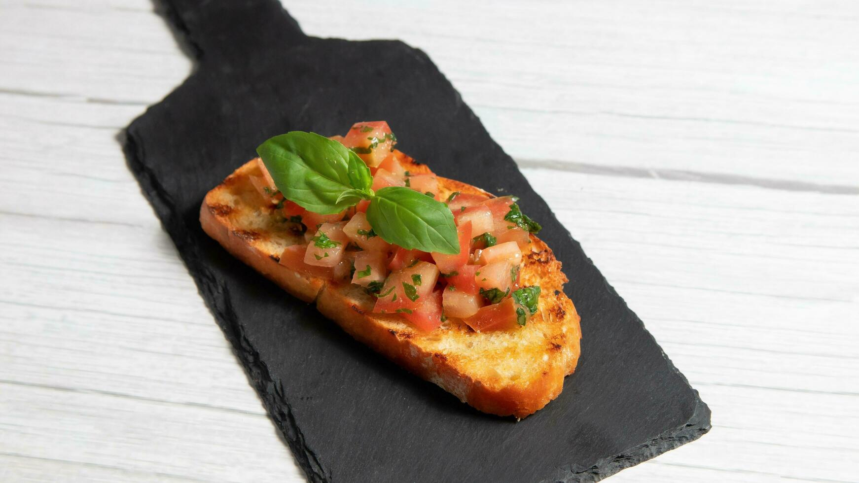 Bruschetta su un' nero piatto, su un' bianca di legno sfondo foto