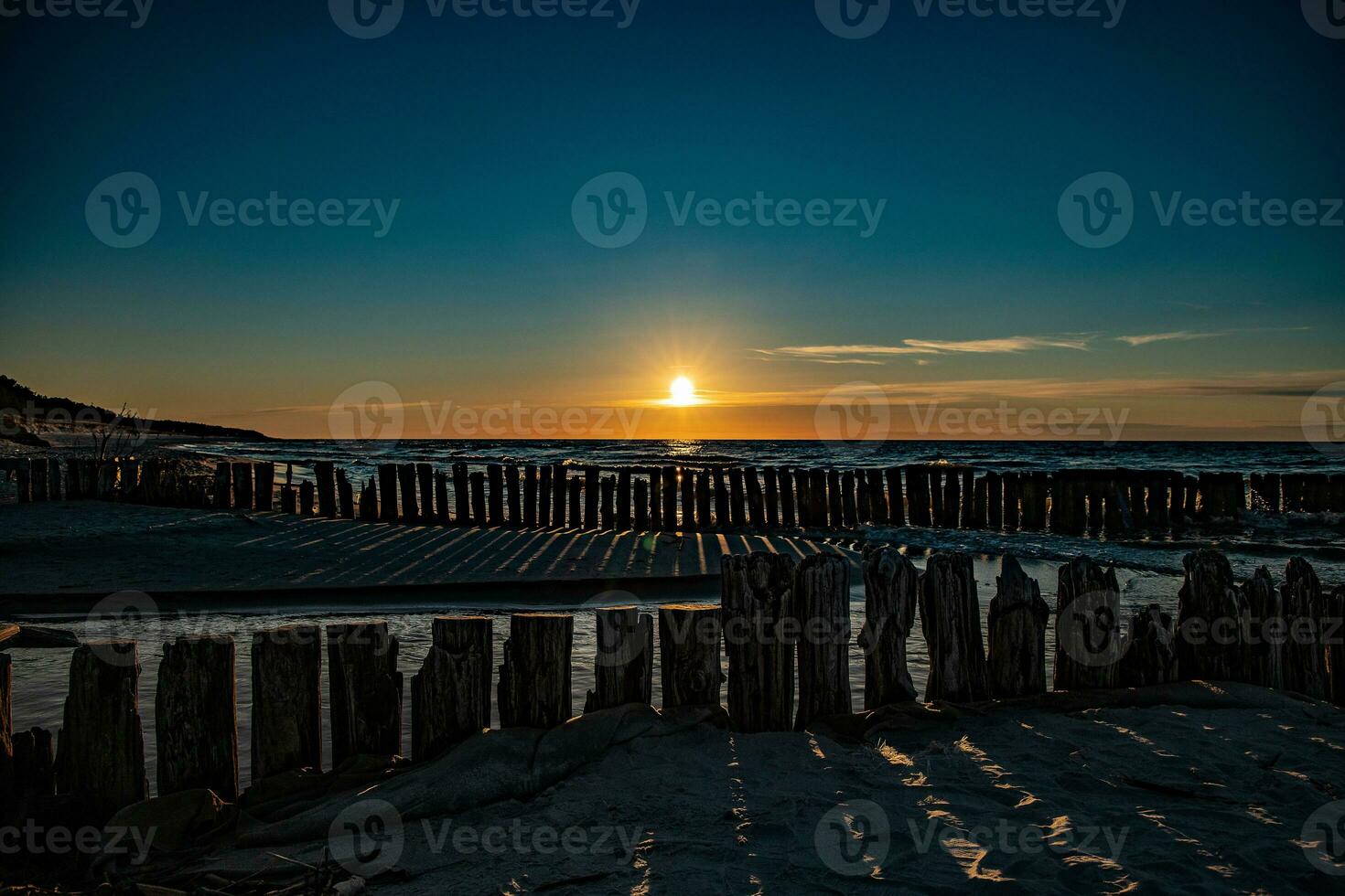 colorato tramonto al di sopra di il polacco baltico mare con buio cielo nuvole e frangiflutti foto