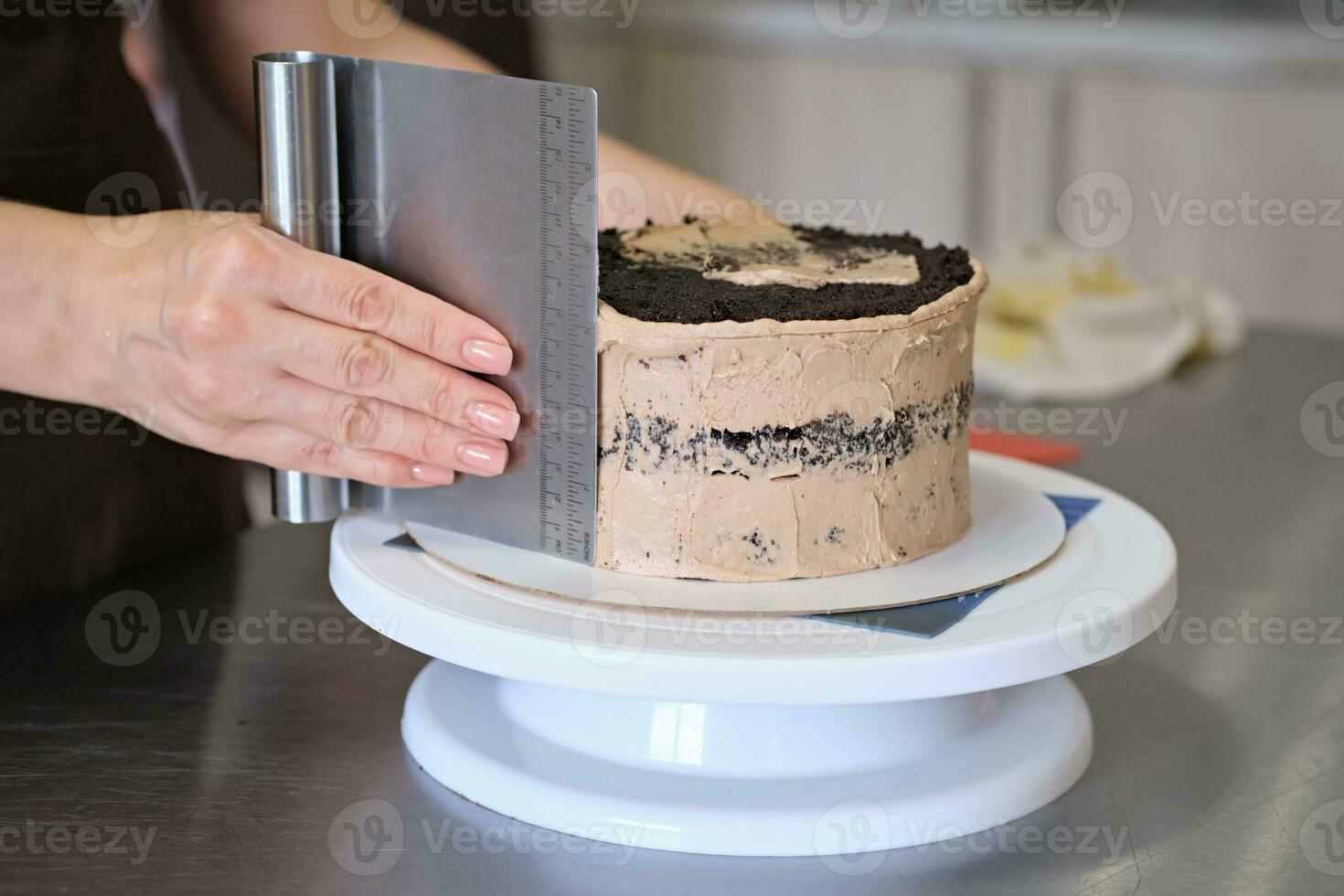 donna Pasticcino capocuoco Linee cioccolato crema su cioccolato torta, avvicinamento. torta fabbricazione processi, selettivo messa a fuoco foto