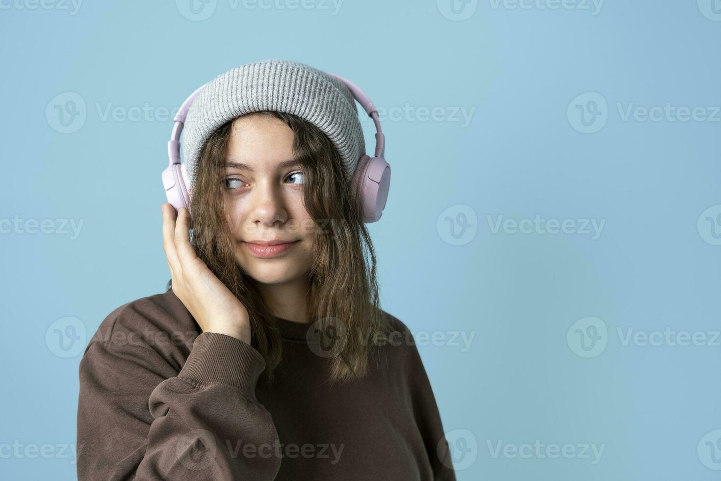 un' carino europeo adolescenziale ragazza nel alla moda a maglia cappello ascolta per musica con senza fili cuffie foto