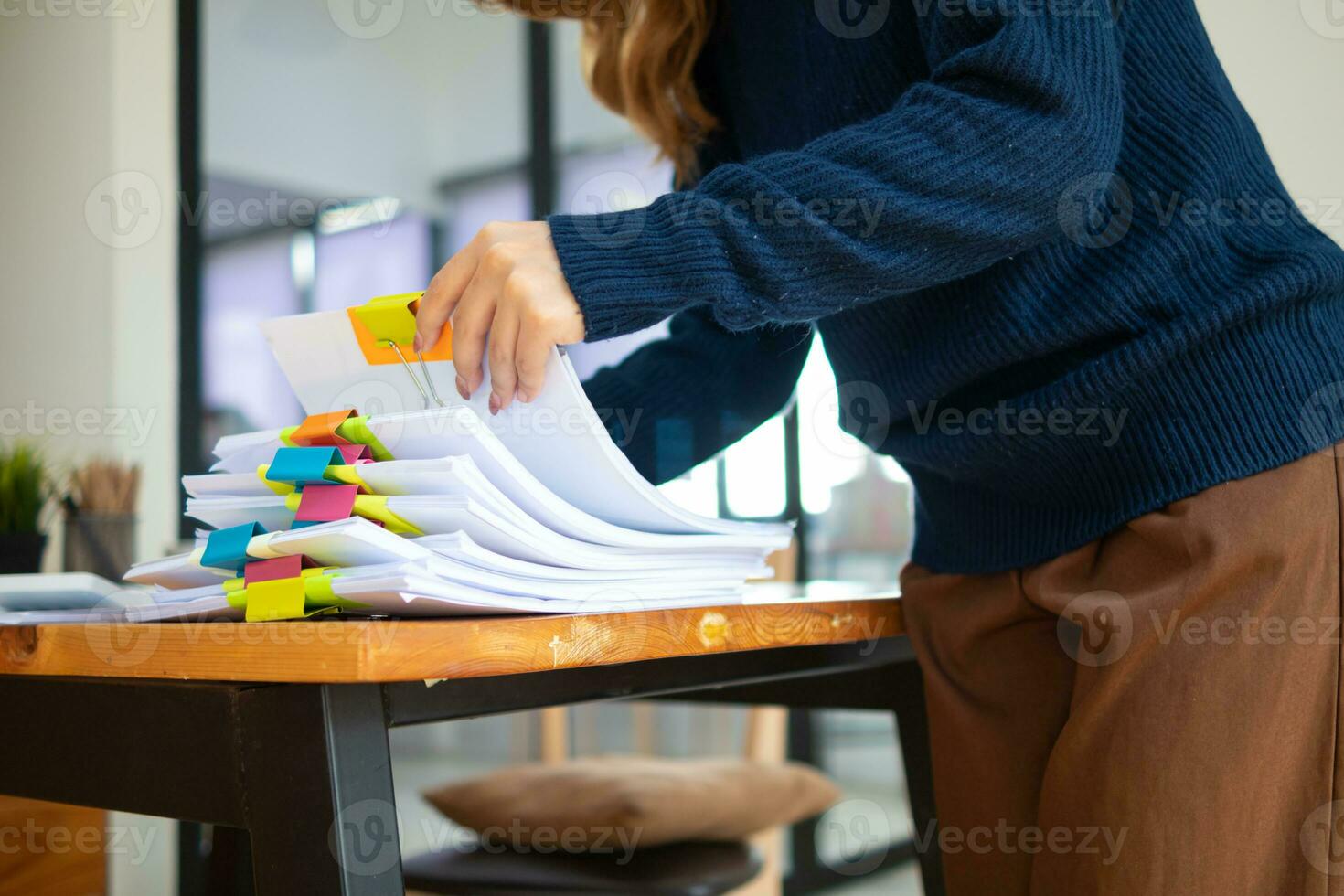 donna d'affari mani Lavorando su pile di carta documenti per ricerca e revisione documenti ammucchiati su tavolo prima invio loro per tavola di registi per uso corretta documenti nel incontro con uomo d'affari foto