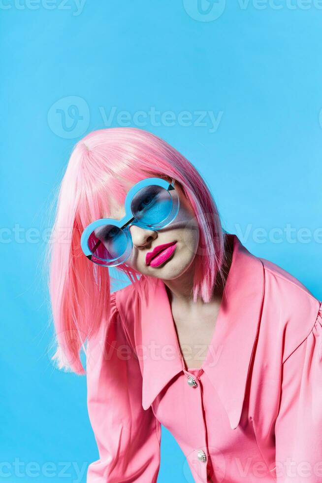 affascinante donna nel blu bicchieri indossa un' rosa parrucca isolato sfondo foto