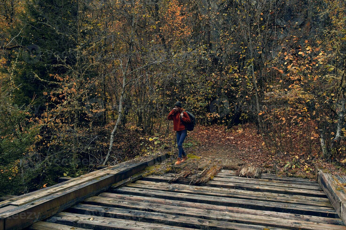 donna turista croci il ponte al di sopra di il fiume viaggio nel autunno foto
