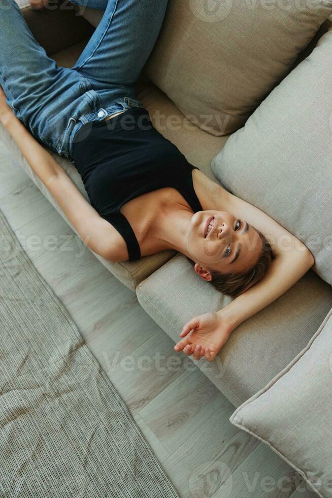 giovane donna con corto taglio di capelli capelli avendo divertimento a casa su il divano Sorridi e felicità, vacanza a casa, naturale in posa senza filtri, gratuito copia spazio foto